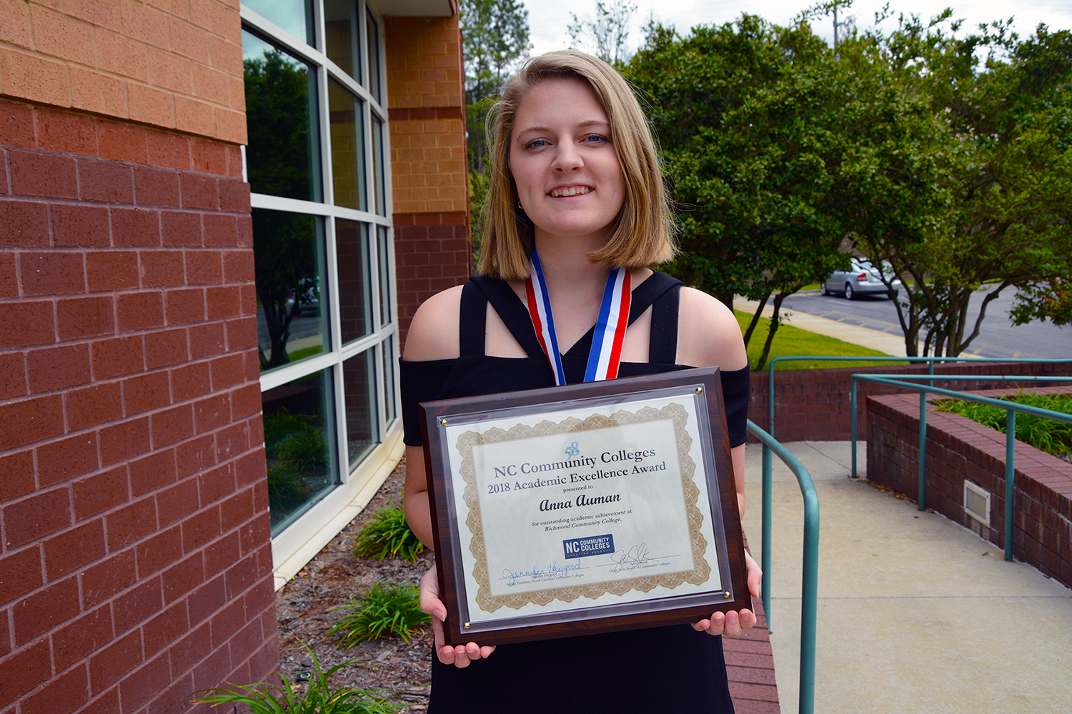 Anna Auman stands outside the Cole Auditorium holding her Academic Excellence Award.