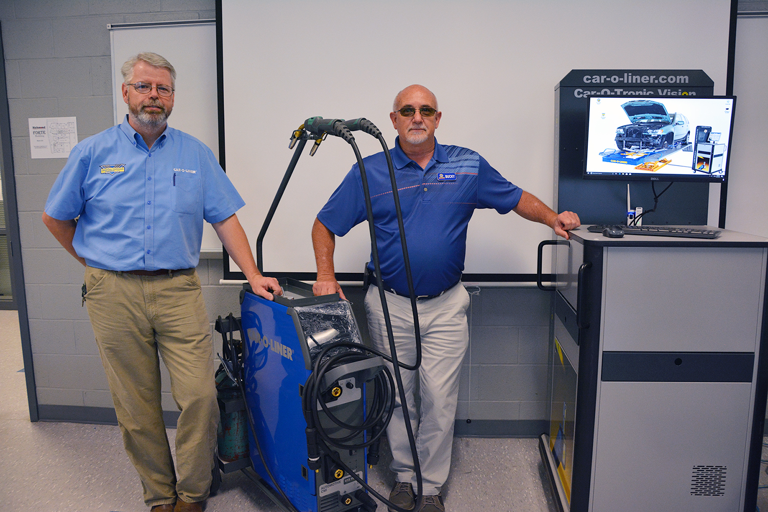 Representatives from Barnes Motor and Parts Co. and Carolina Collision Equipment stand with welding tools