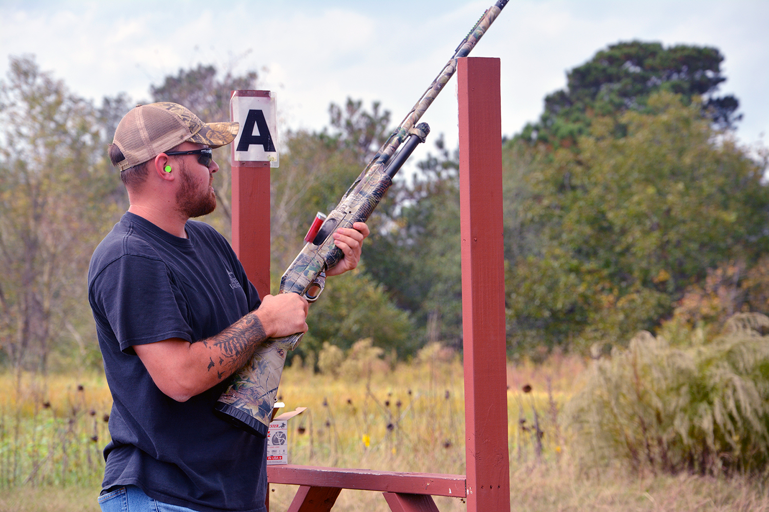 A shooter stands at one of the clay shoot stations.
