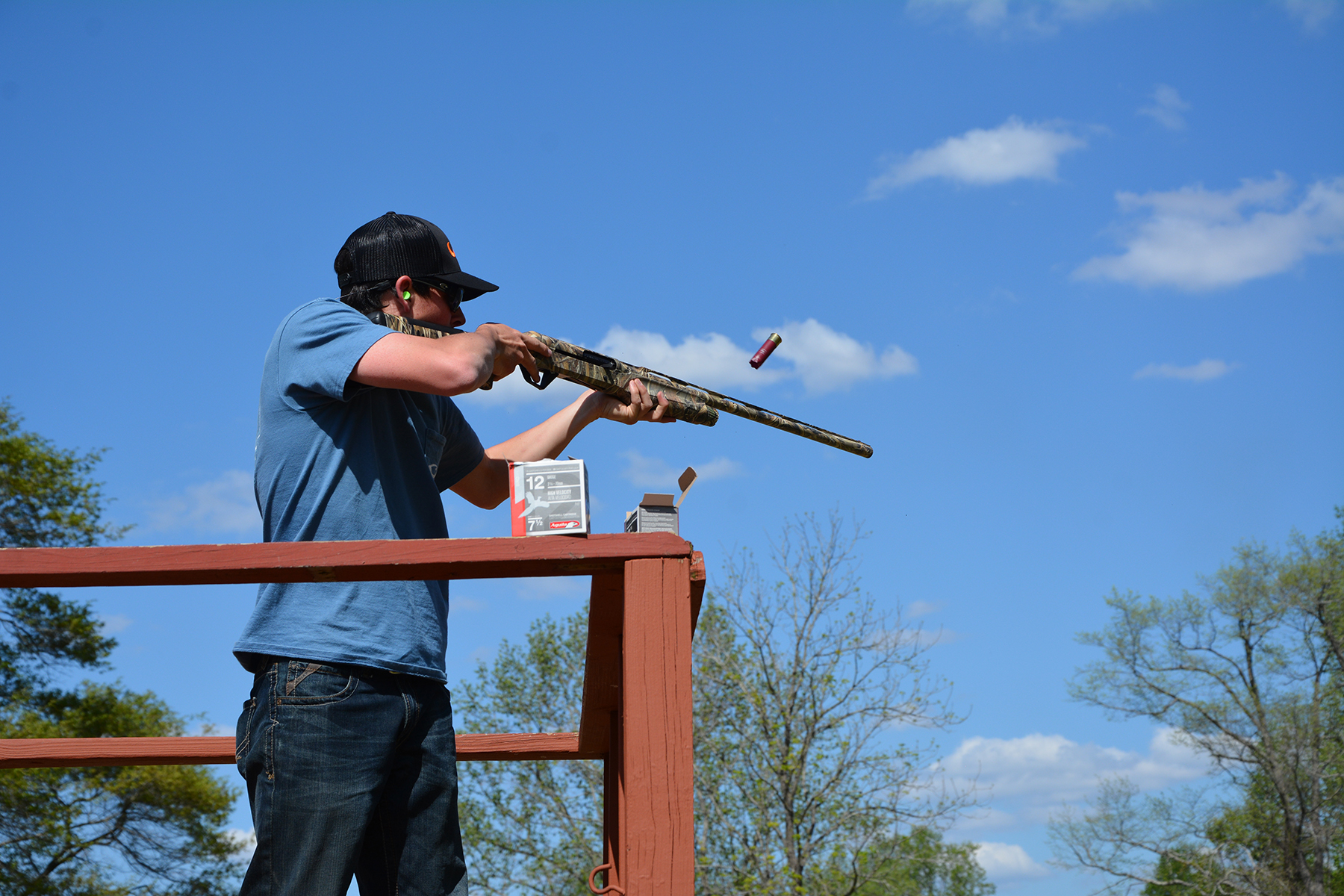 Young man shooting a shotgun at clay skeets