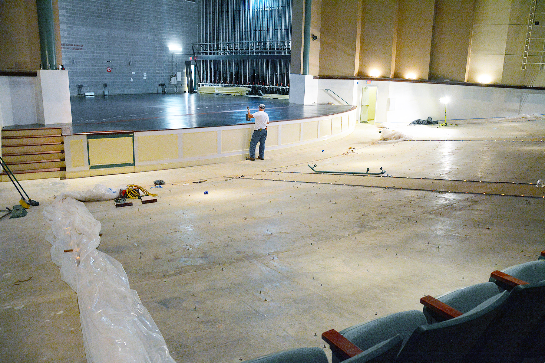 A painter paints the front of the stage in the Cole Auditorium.
