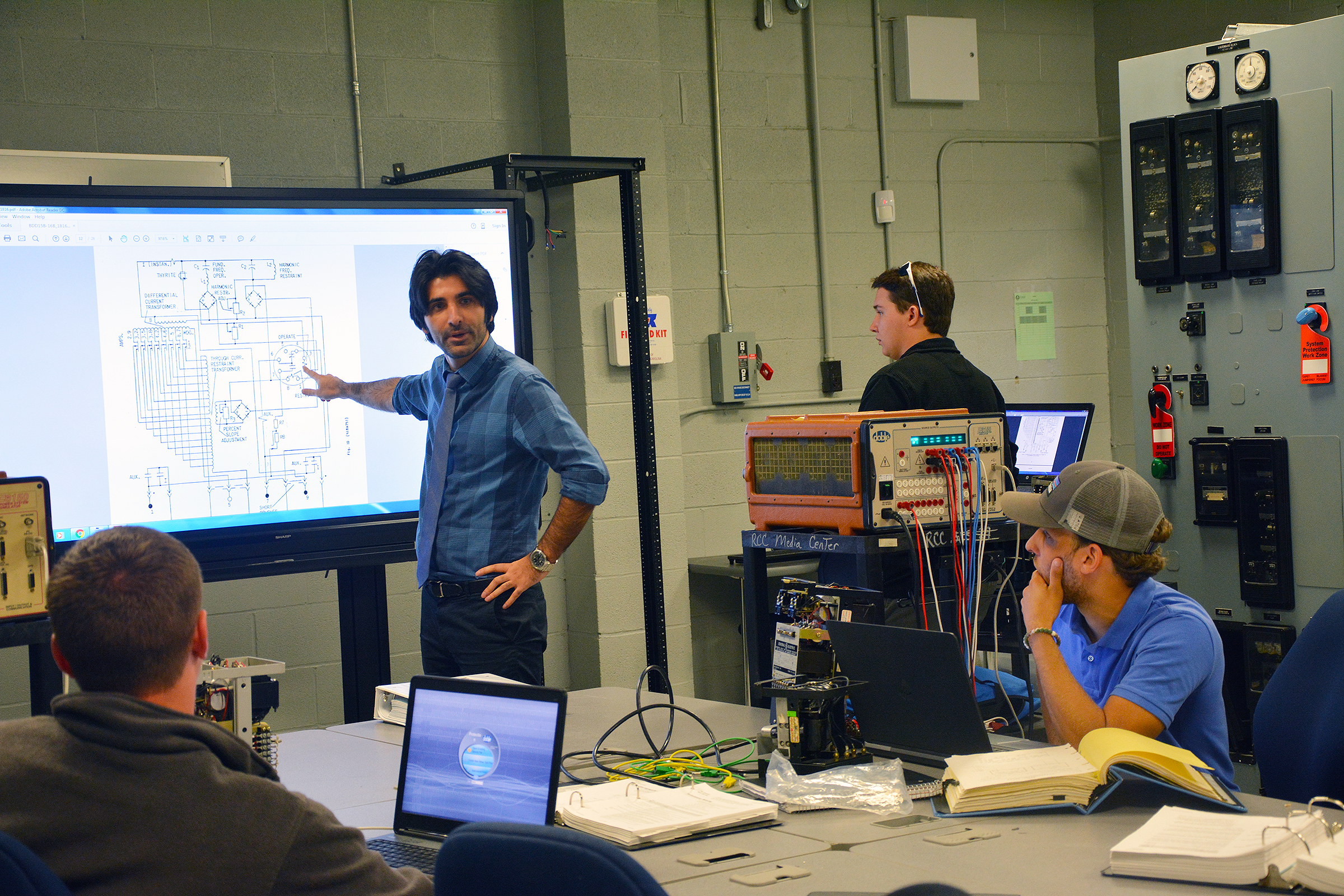 Richmond Community College instructor Morteza Talebi points to a diagram in a class of Electric Utility Substation and Relay Technology students.