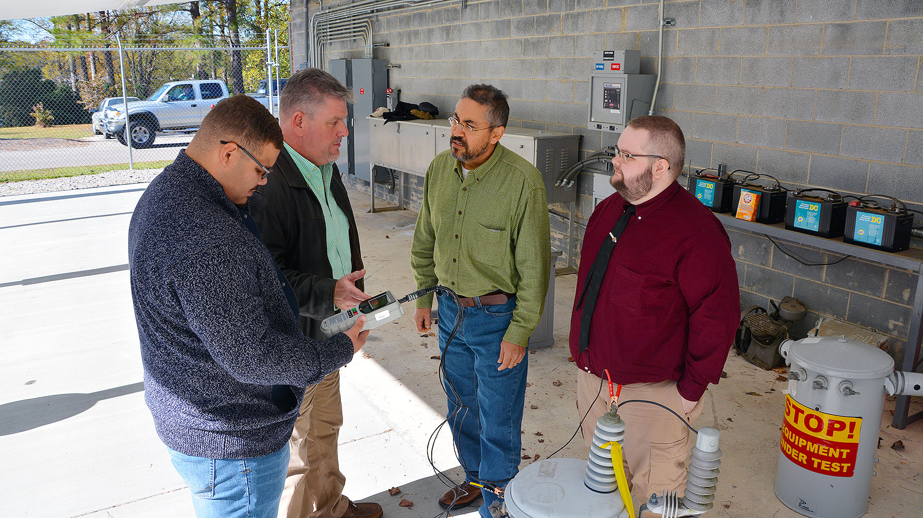 EUSRT students and instructor stand in substation with test device