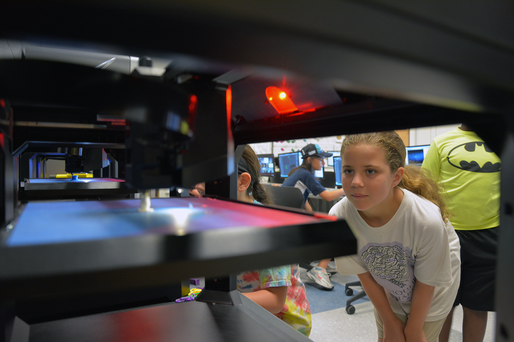 A young girl watches an object print out on the 3D printer