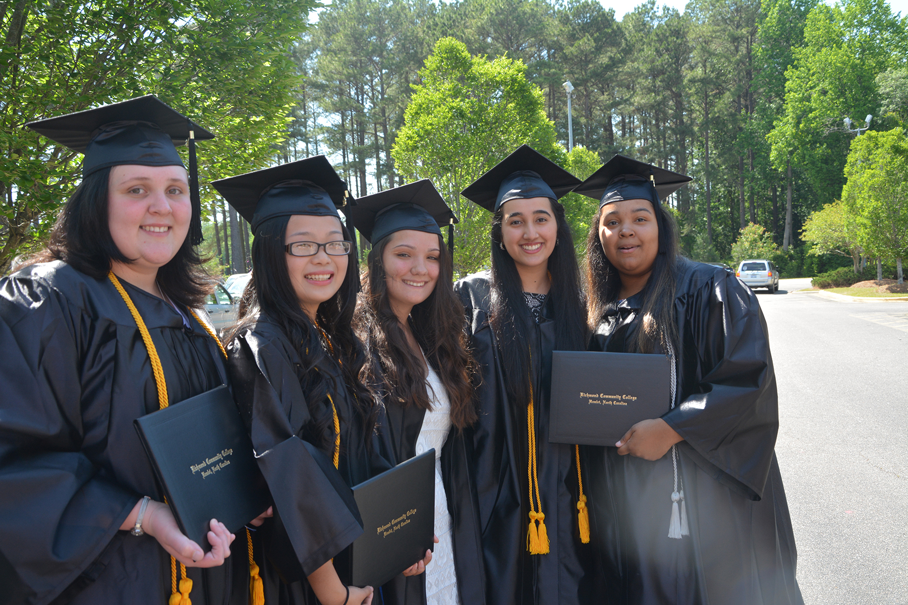 A group of graduates in cap and gown stand for a photo