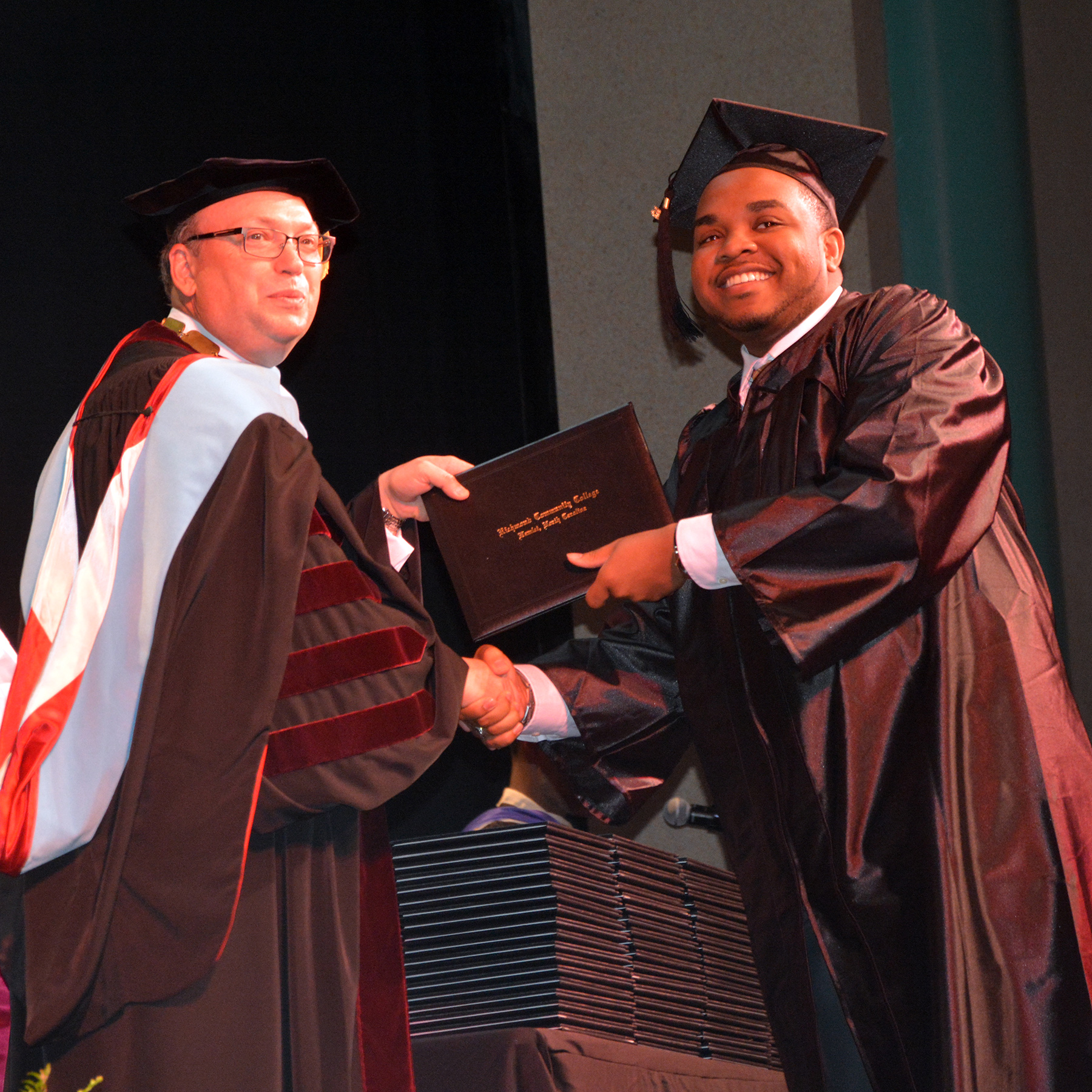 Richmond Community College graduate receives a diploma from College President Dr. Dale McInnis.