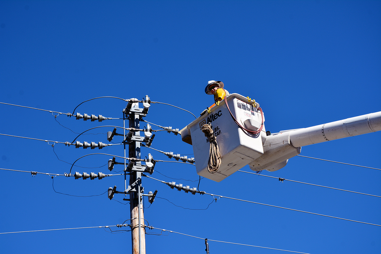 An electric lineman goes up in a bucket to work on power lines