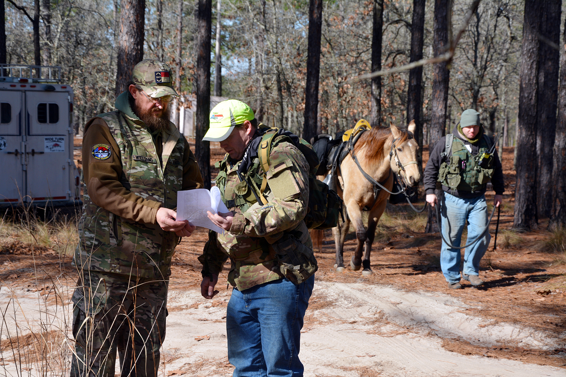 Search and rescue team members consult a map before heading into the woods on horseback