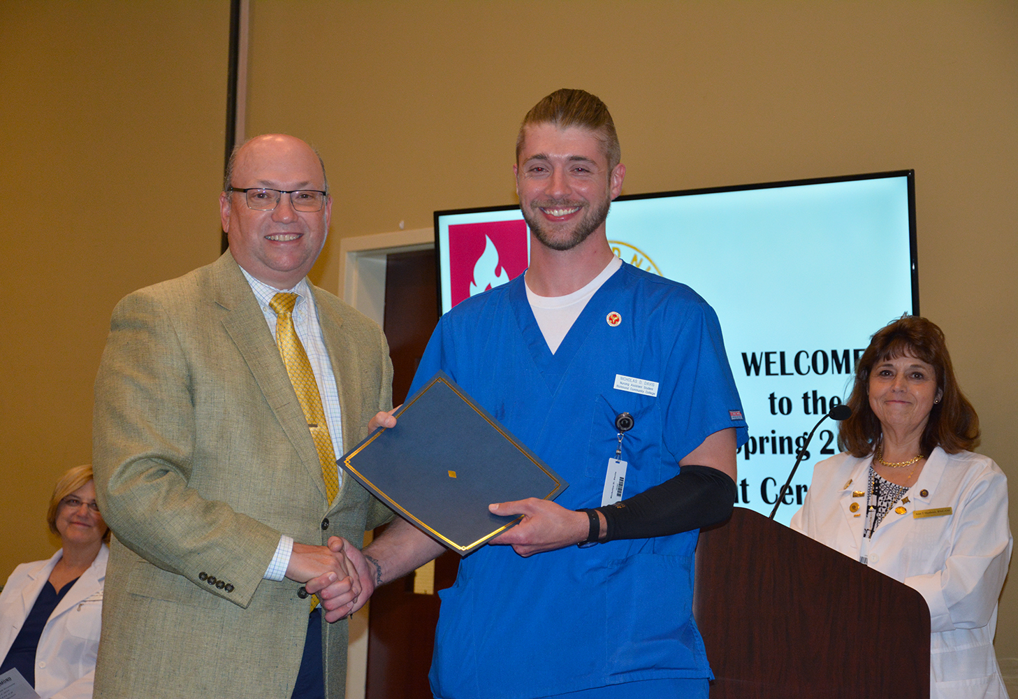 Richmond Community College nursing assistant student Nicholas Davis shakes hands with Dr. Dale McInnis, president of the College, during the pinning ceremony held for students completing the program. Pictured also is Ann Hudson, an instructor for the Nursing Assistant program.