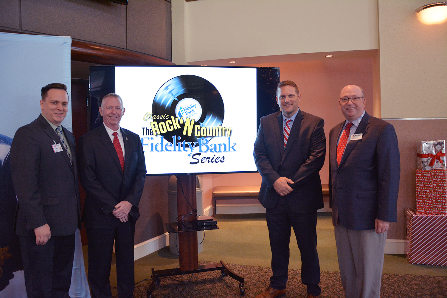 Fidelity Bank executives and RichmondCC leaders stand together with the Classic Rock'N Country concert series logo.