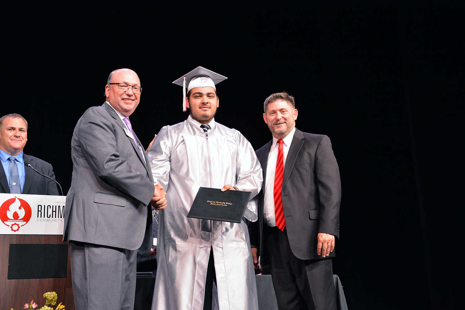 Cruz Titus holds his diploma and shakes hands with the college president.