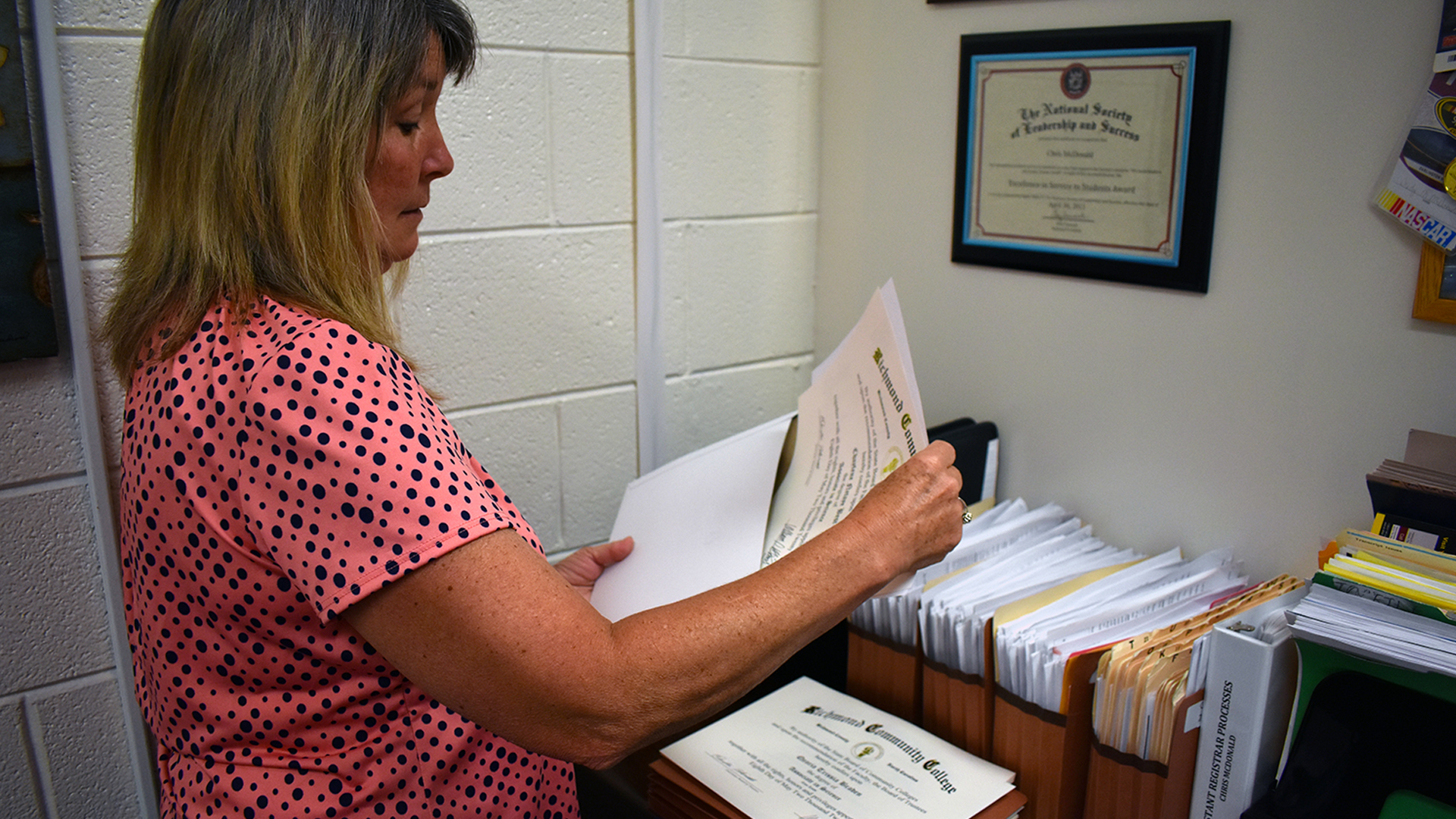 Assistant Registrar puts a college degree into an envelope.