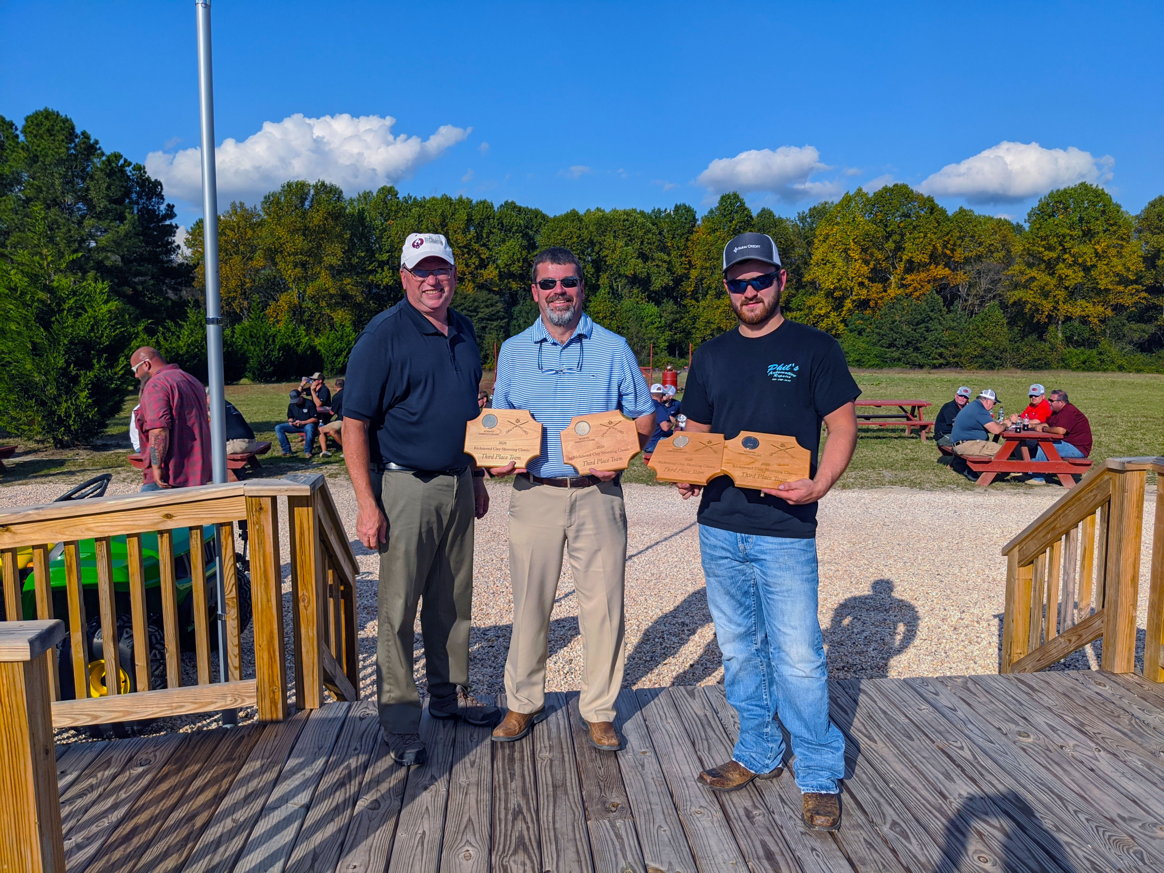 Clay shoot third place winners hold their trophies