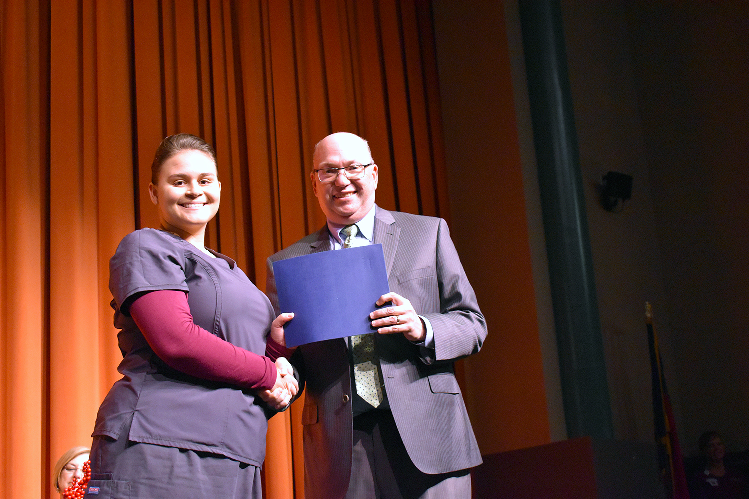 Nursing Assistant student receives certificate and shakes hands with College president