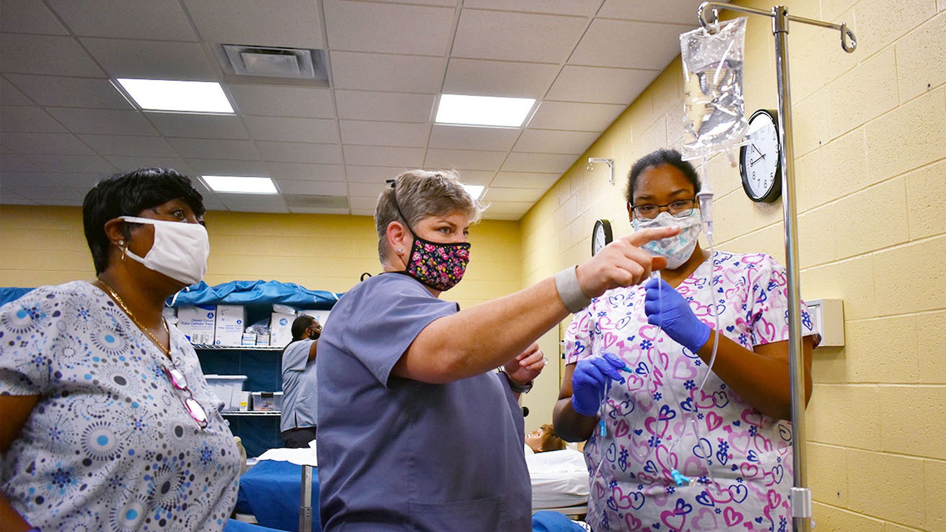 Nursing students and nursing instructor study the proper procedure for an IV bag.