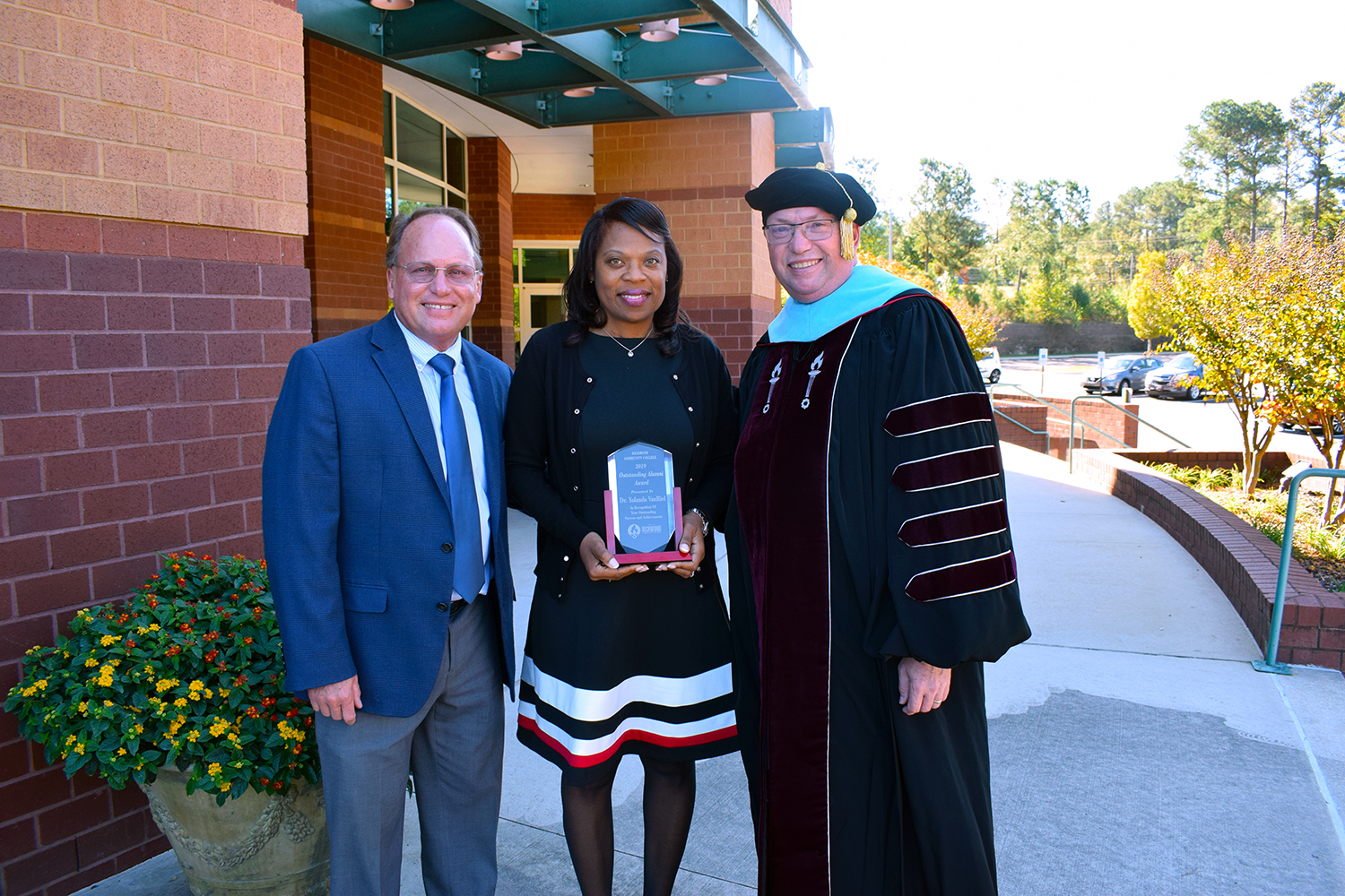 College leaders stand with Dr. VanRiel, who holds her Outstanding Alumni Award
