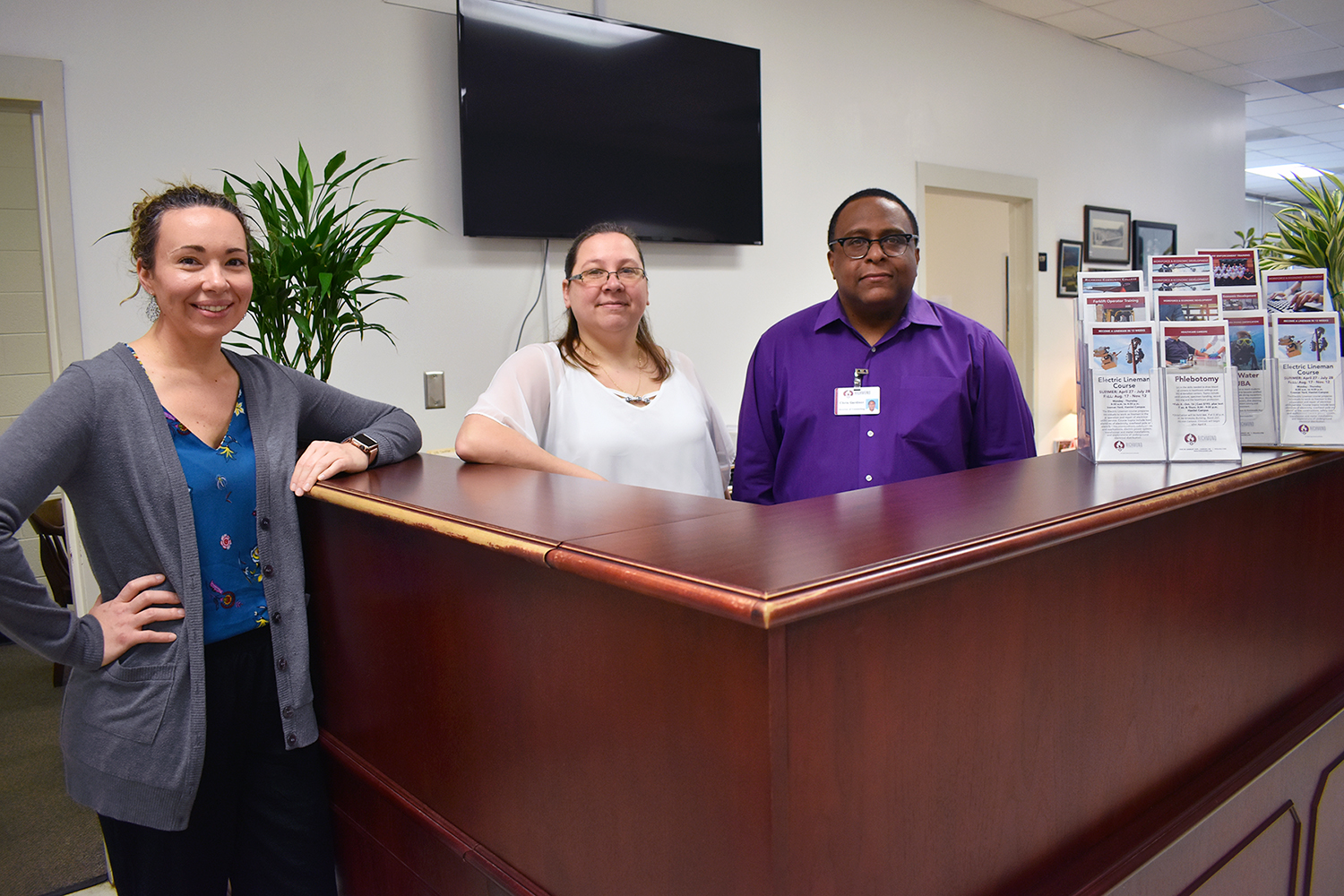 Three counselors stand at a desk in Student Services.
