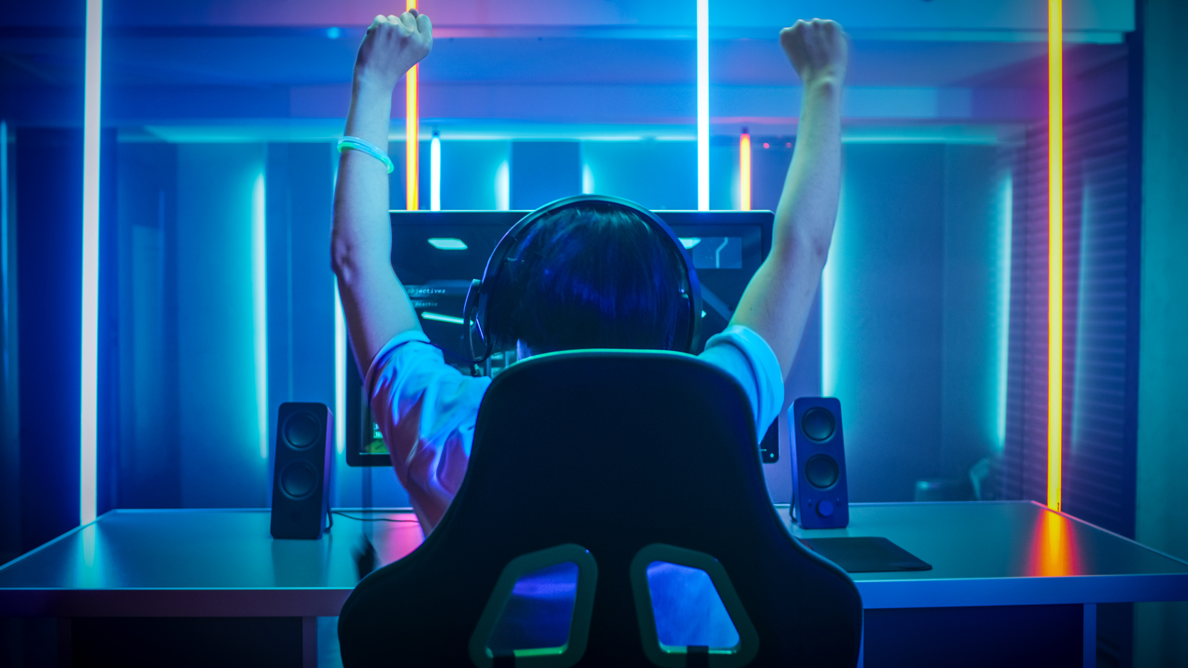 Gamer sitting in chair with hands raised in victory