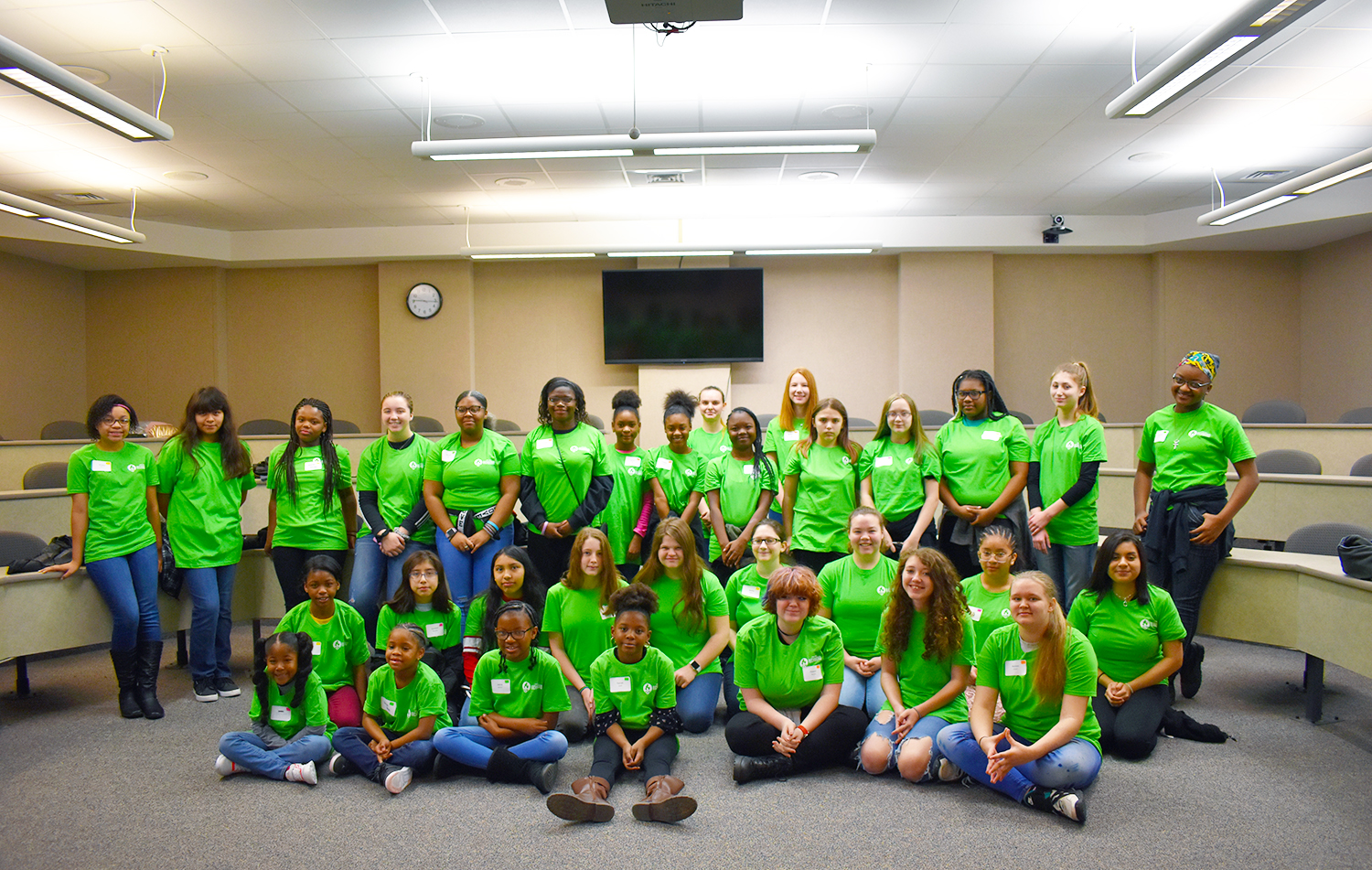 Girls Exploring Engineering all wearing green t-shirts pose for a photo.