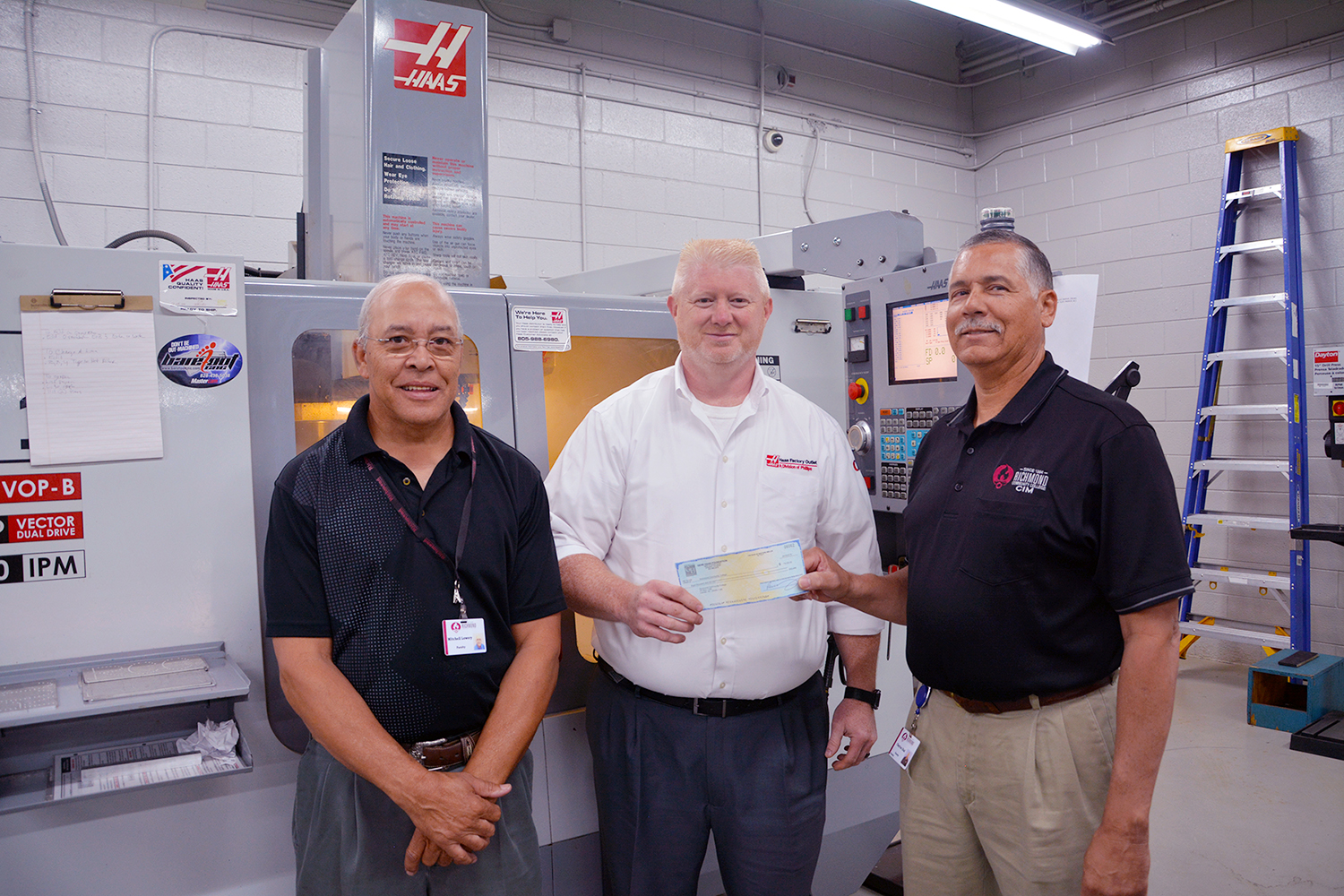 Haas Foundation representative presents check to the two machining instructors