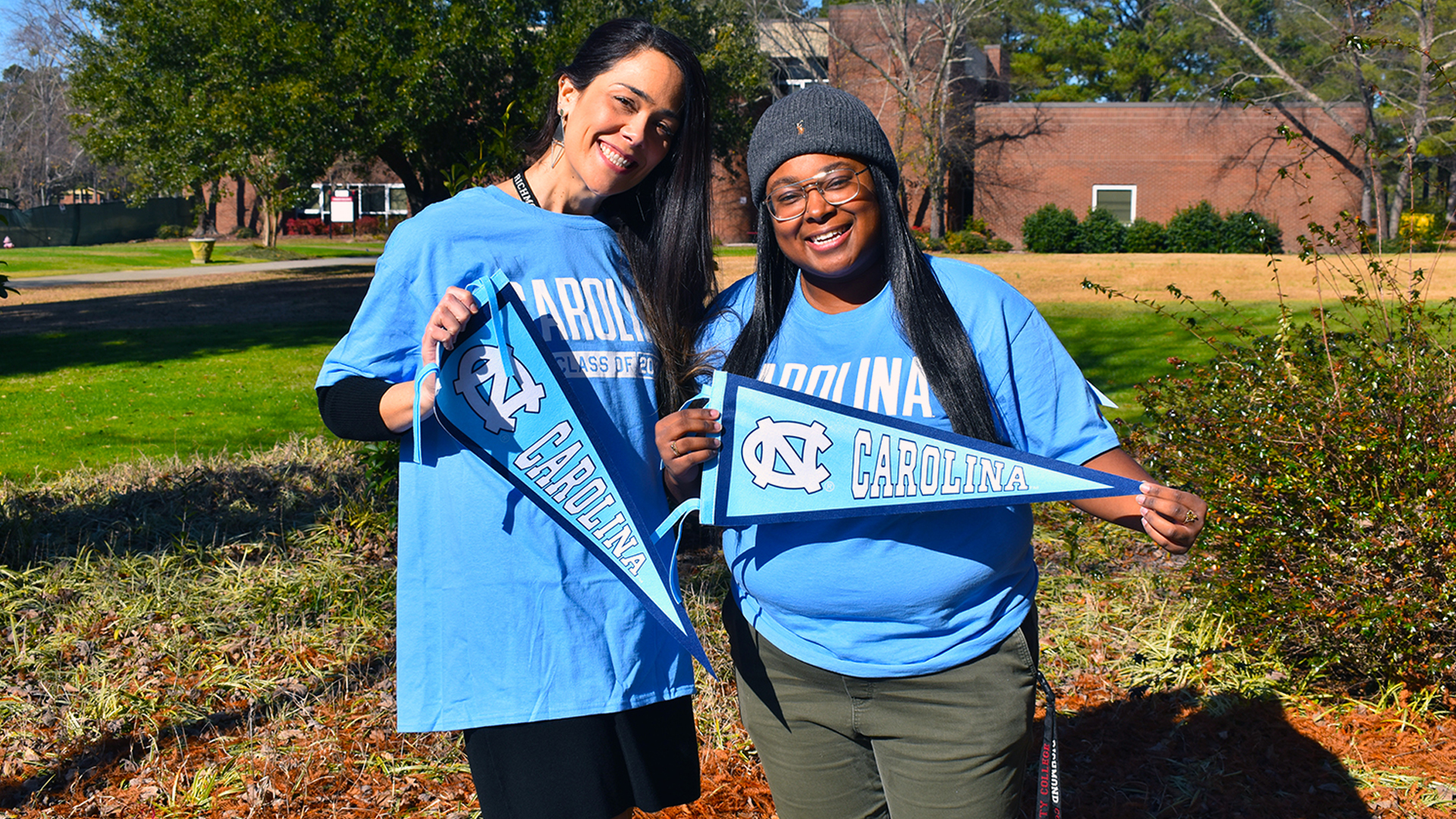 Dr. Watts and Kimani Spruill hold up Carolina pennants. 