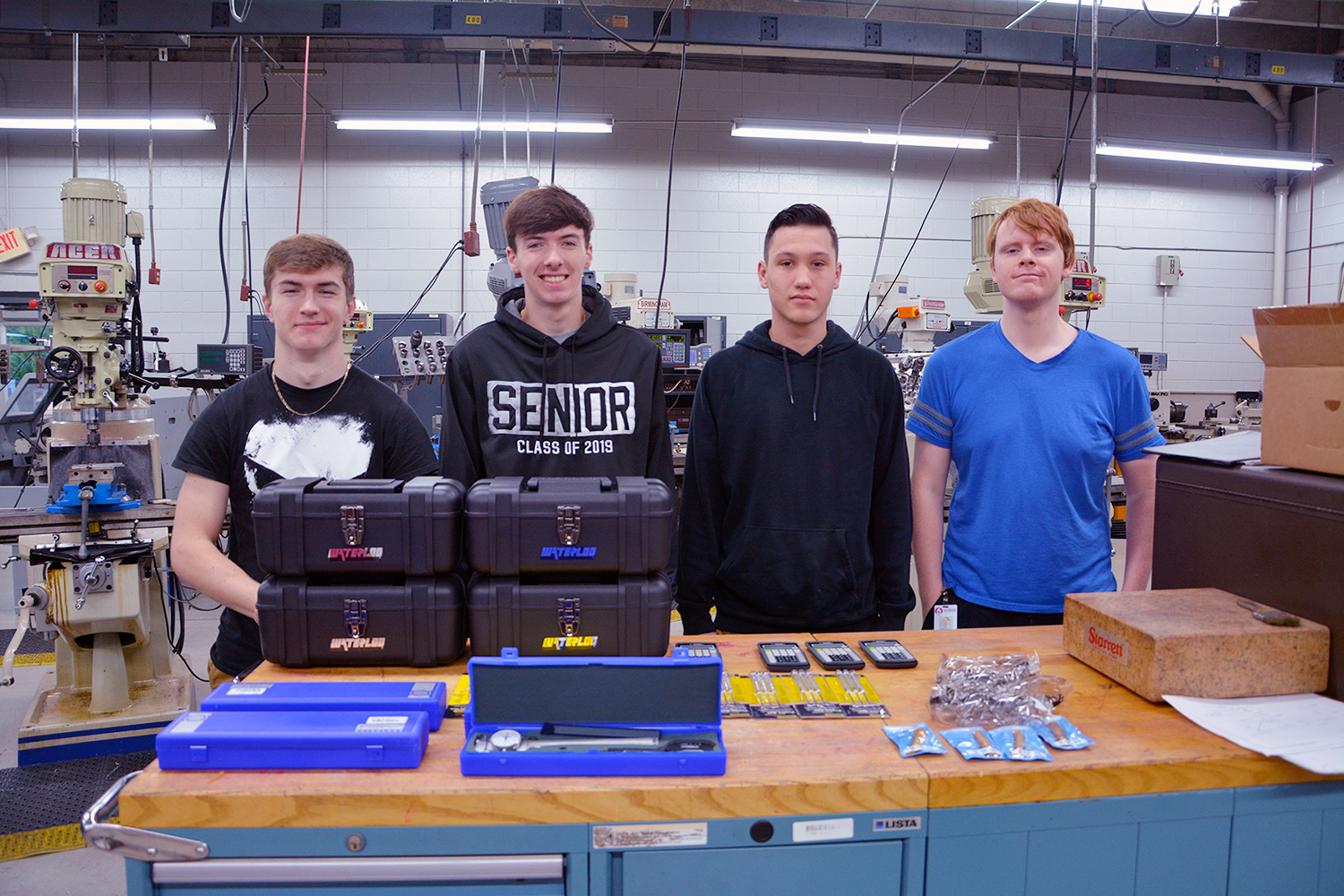 High school students stand with the tool box and tools they received in the machining program.