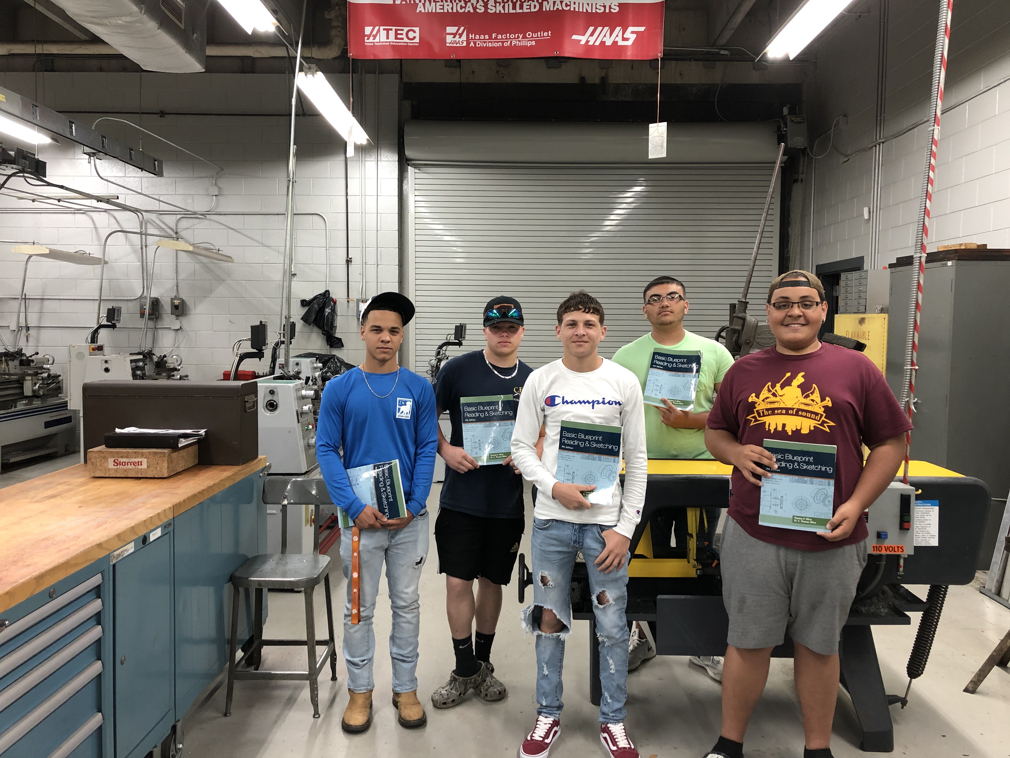 High school students hold the free workbooks they received in the machining program.