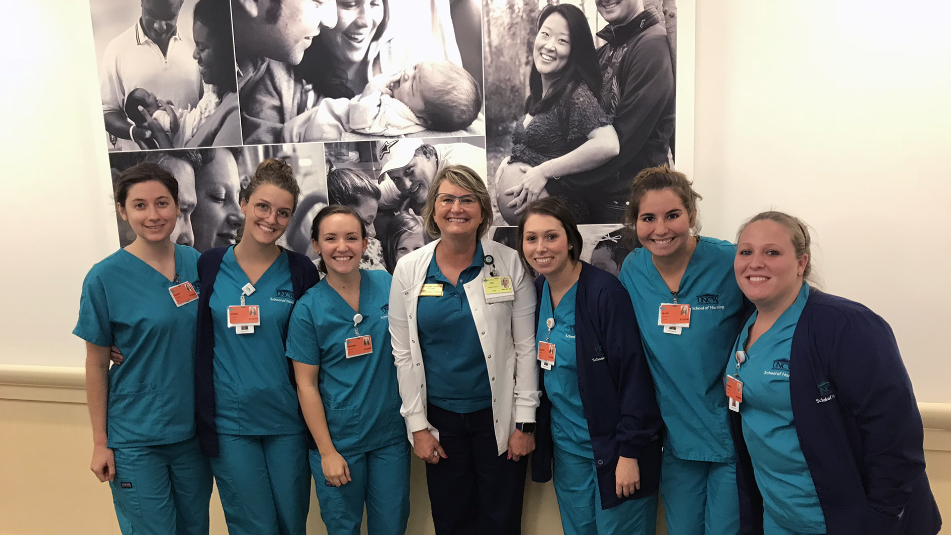Nursing students stand with a nursing instructor in a hallway