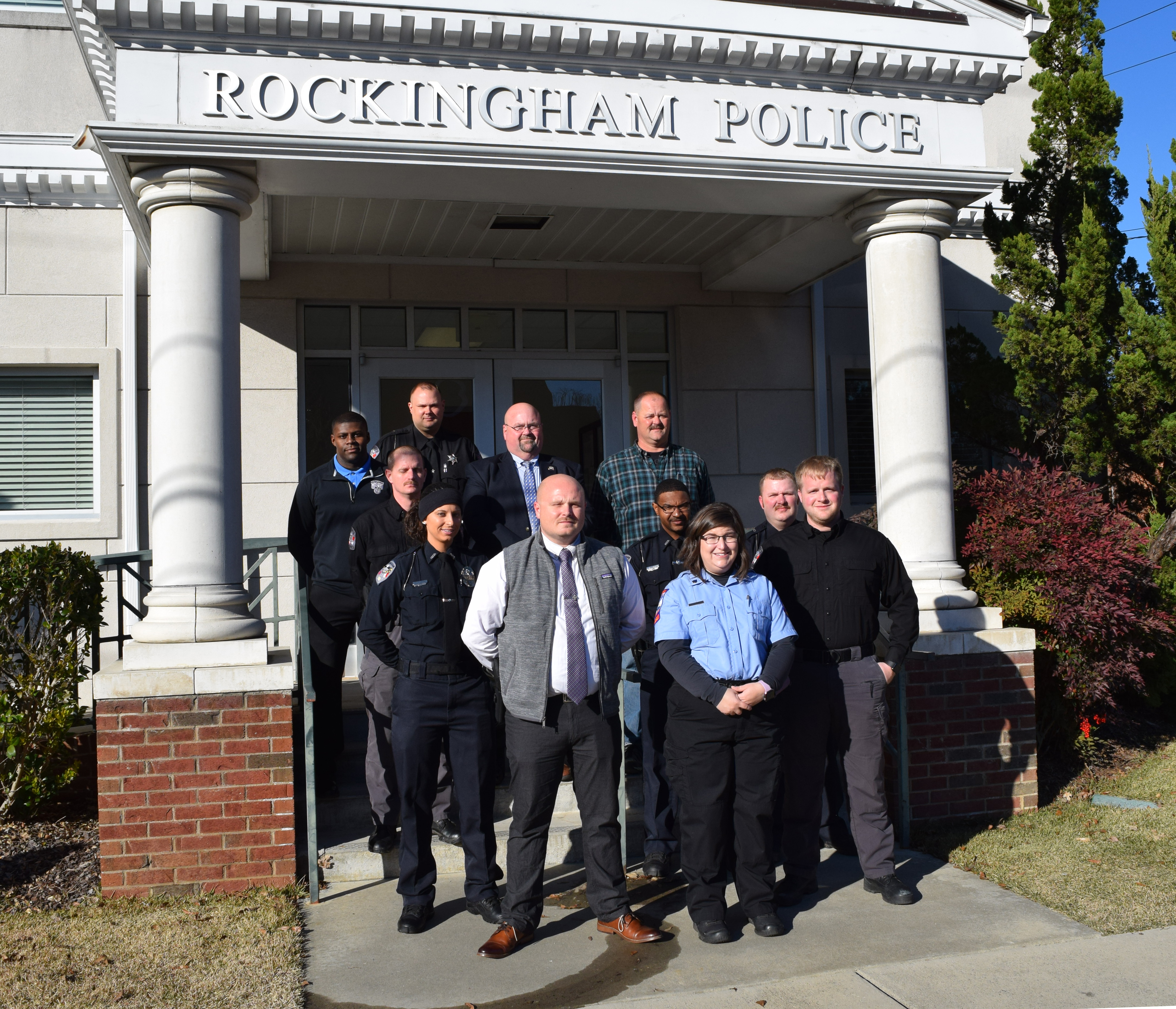 First responders stand on the steps of the Rockingham Police Department.