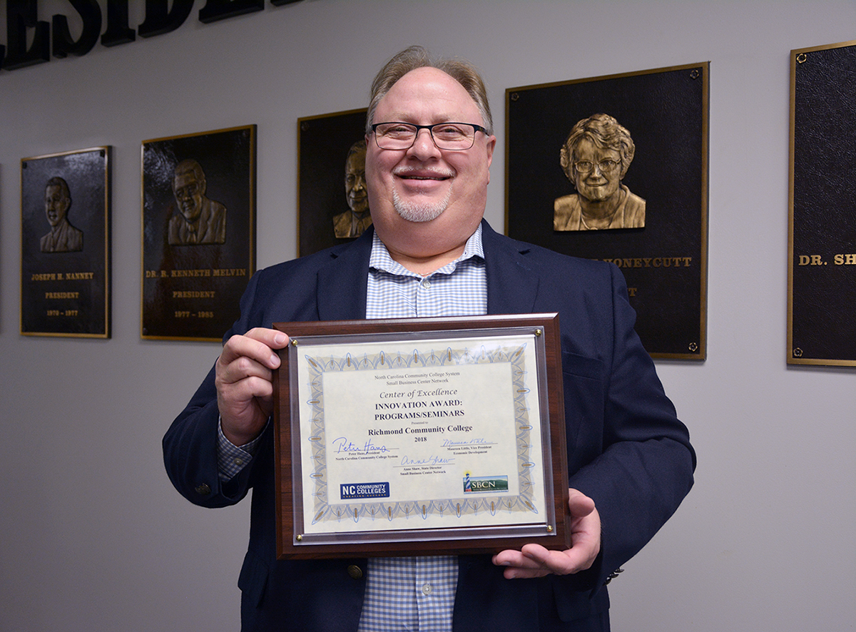 Small Business Center Director Butch Farrah holds the state award for innovative programs