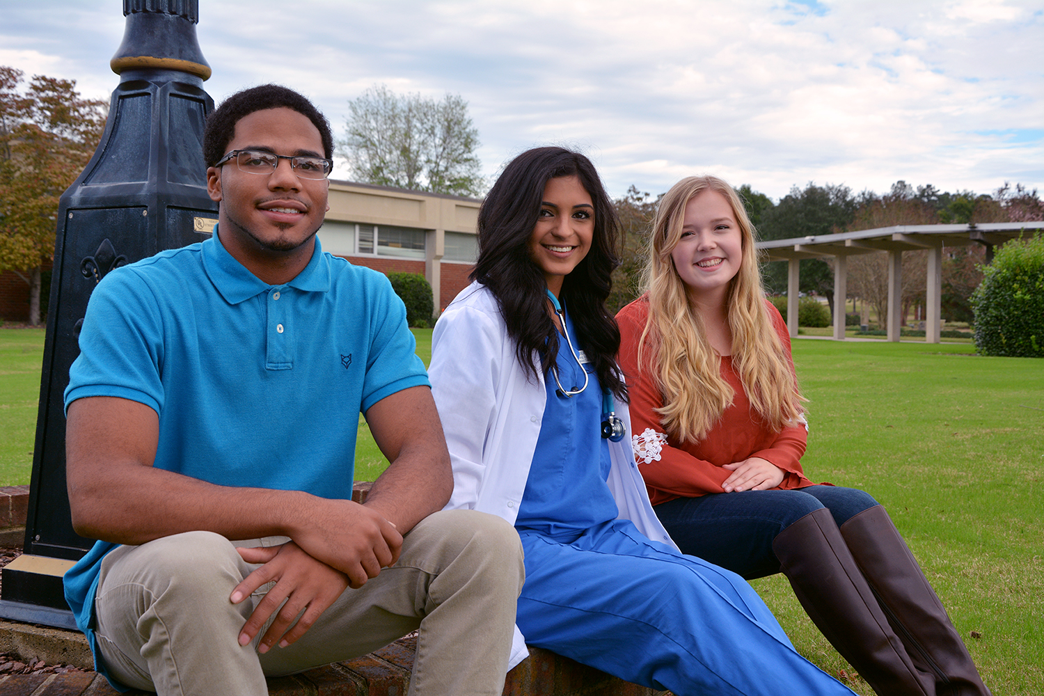 Photo of three students sitting by the clock on main campus