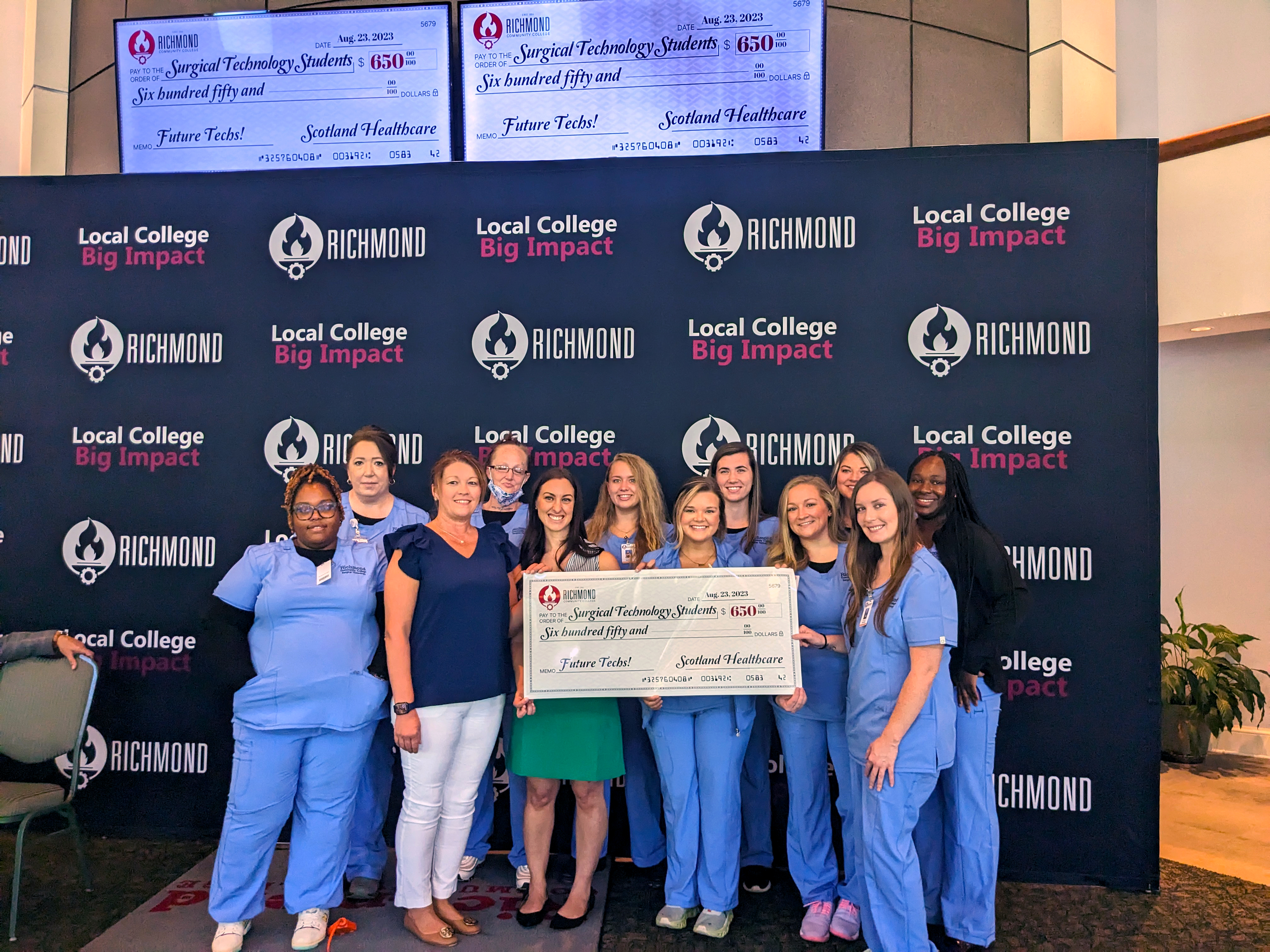 Surgical Tech students stand with big check.