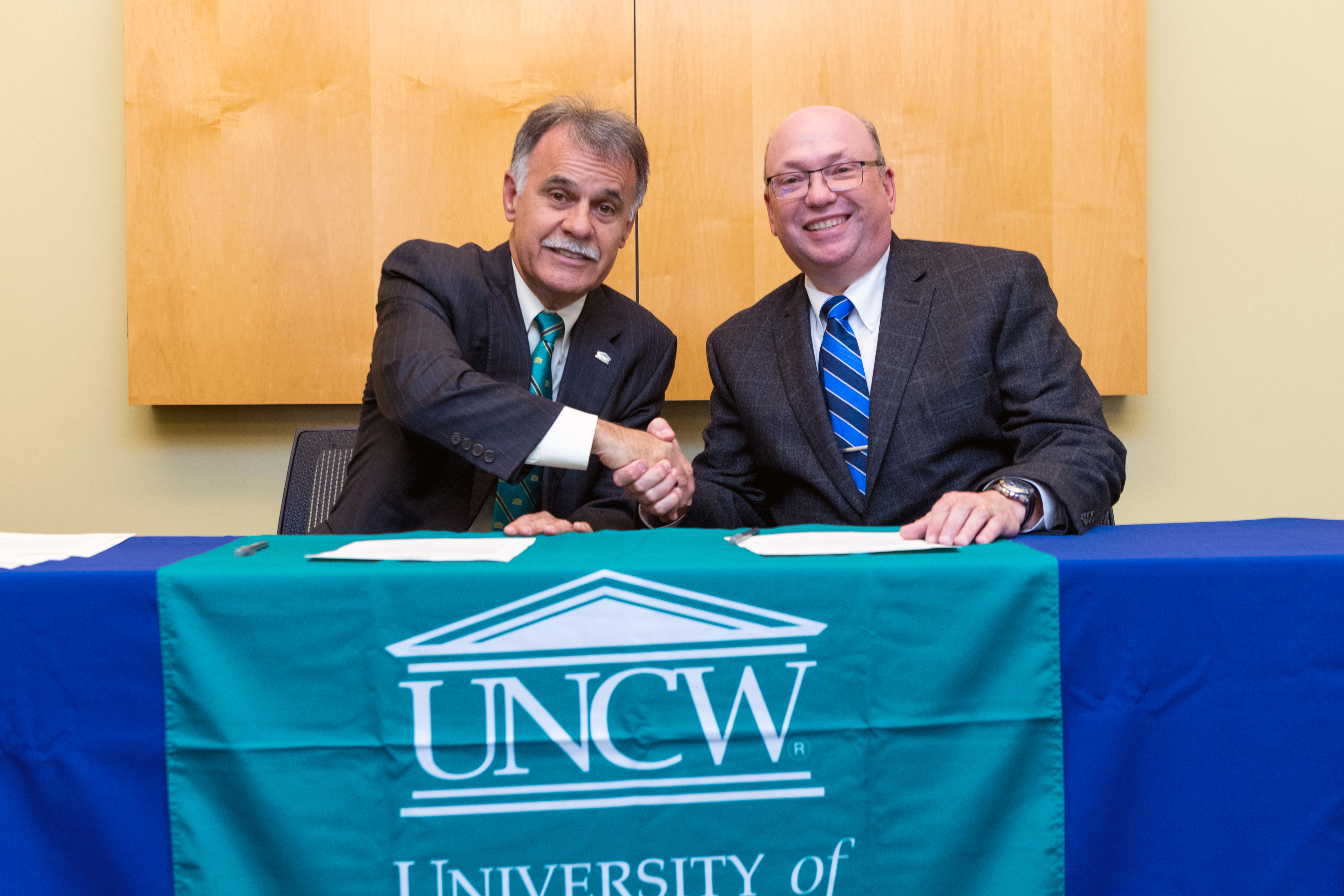 The UNCW Chancellor and the RichmondCC President pose together at a table.