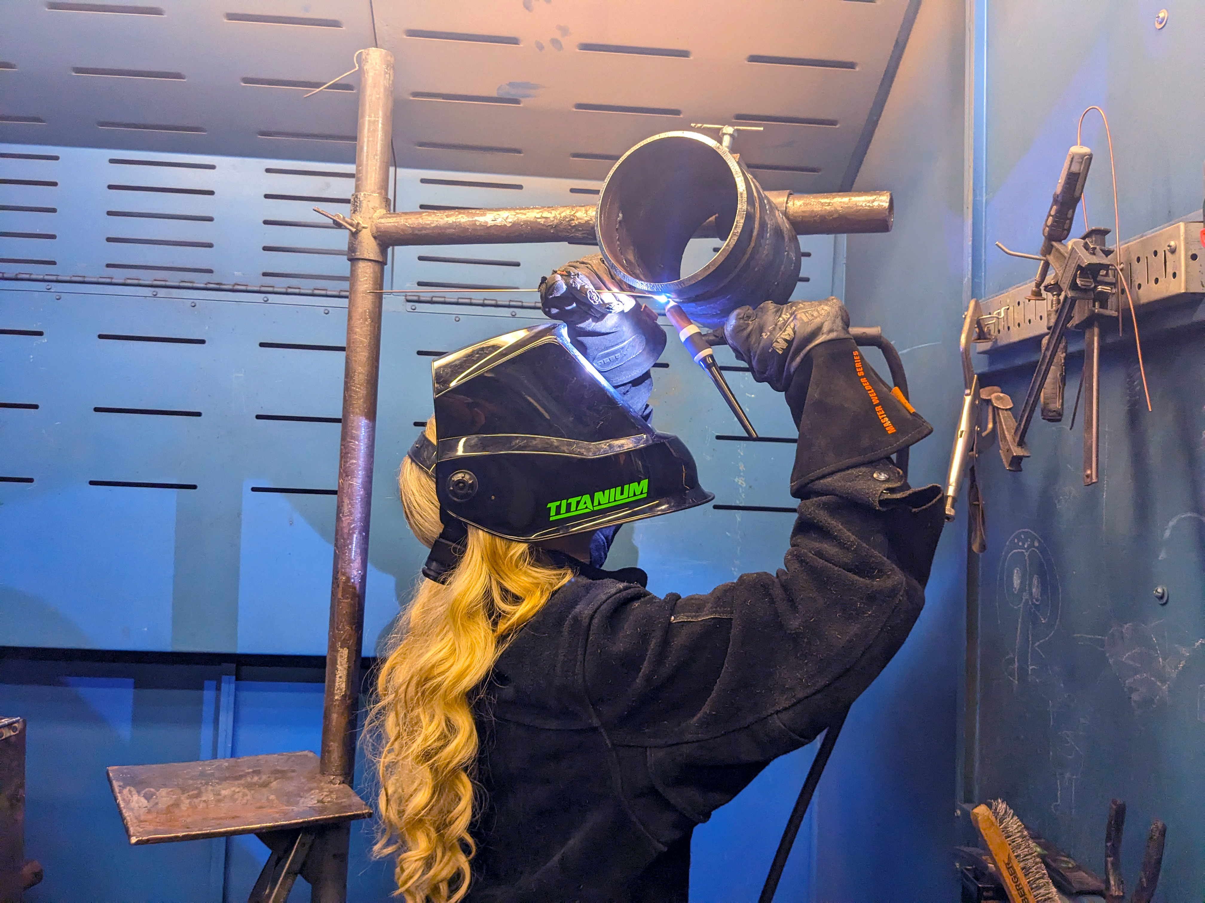 Female welder works on a piece of metal