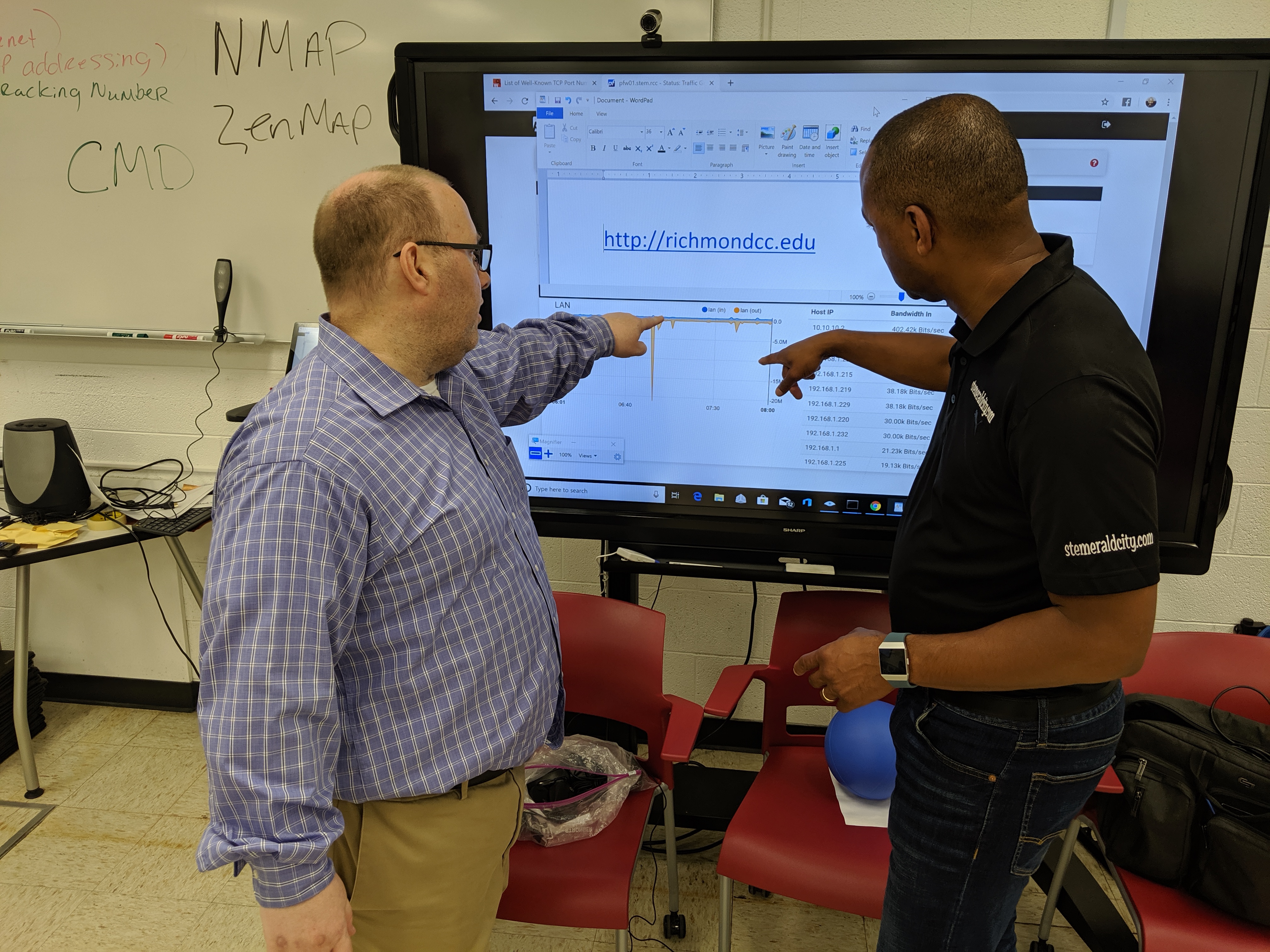 Brian Goodman (left) and Jeff Epps (right) view the impact of students sending large packets of information to a server on a network the students built themselves.
