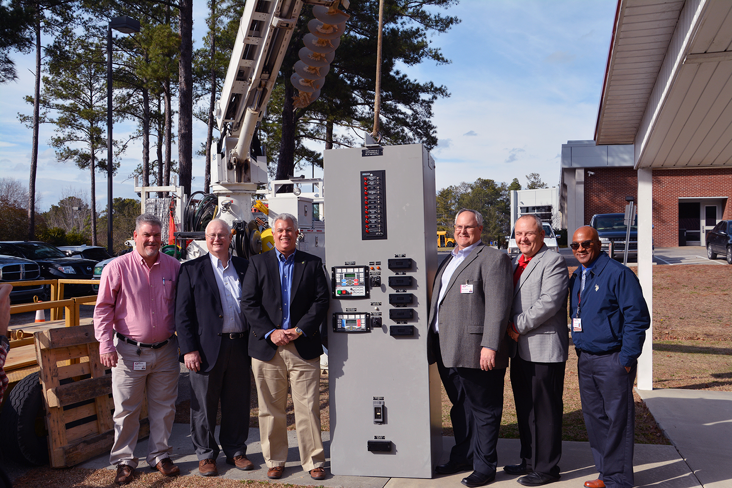 College leaders and Pee Dee Electric company leaders stand with donated relay panel in substation