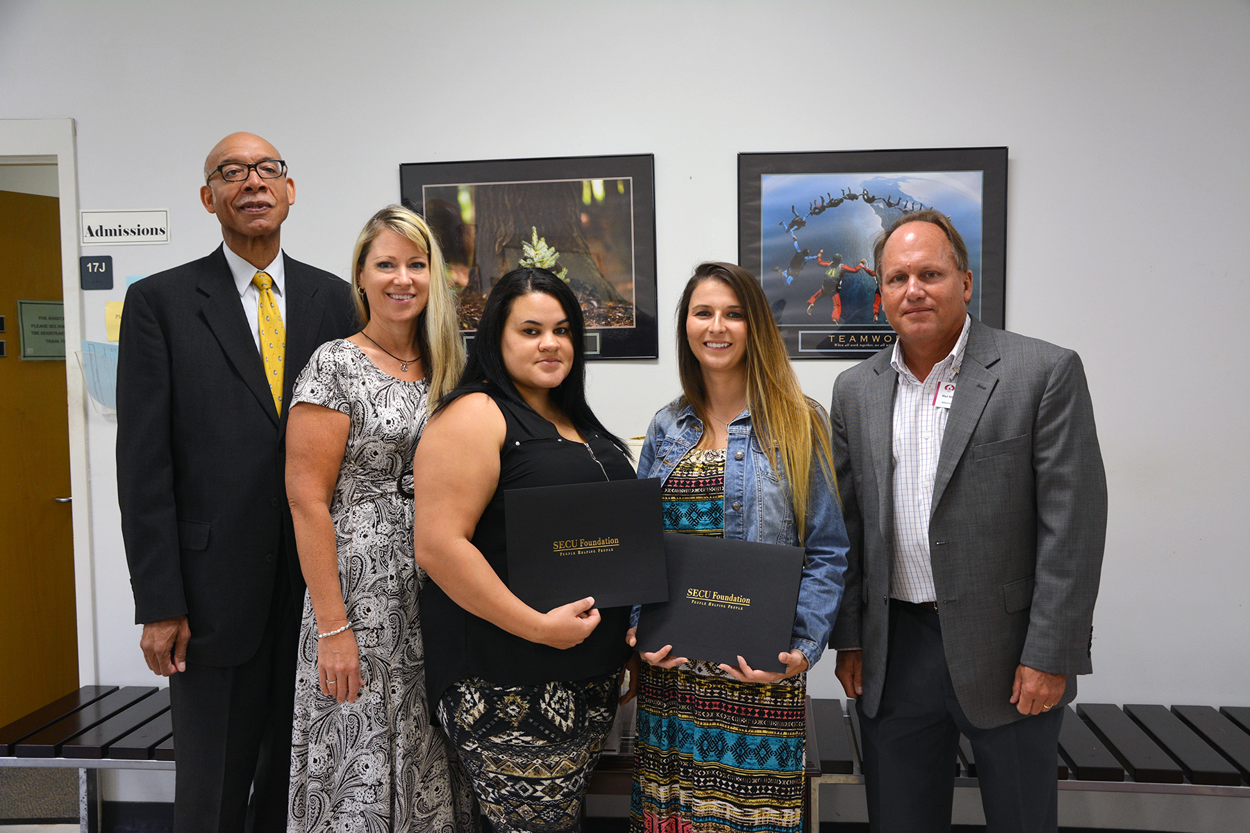 Representatives from the credit union stand with two scholarship recipients