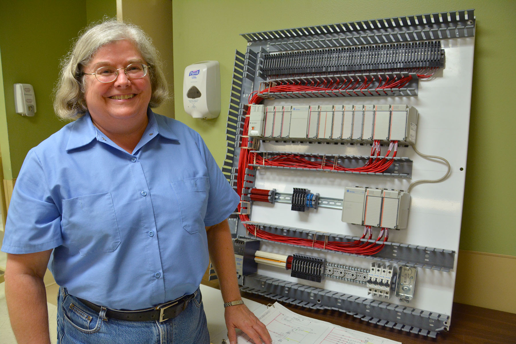 : Shirley Koch of Laurinburg stands beside an industrial panel she worked on for Pittman Electrical Inc. Using the skills she learned in the NCCER Electrical Apprenticeship program offered through Richmond Community College, Koch installed and wired all the components on the panel that will be used by Railroad Friction Products.