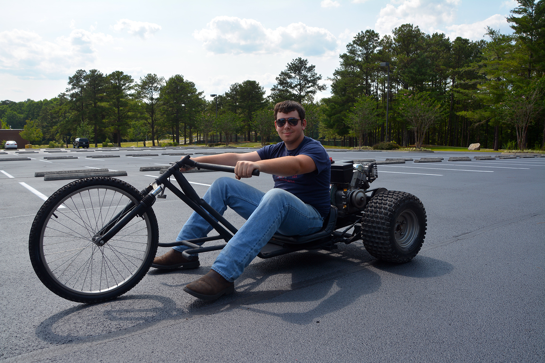 Richmond Community College student Travis Butler sits on the trike that he and his classmate, Jason Felts, built in their welding class. They built the motorized trike using bicycle, lawn mower, go-cart and other scrap parts.
