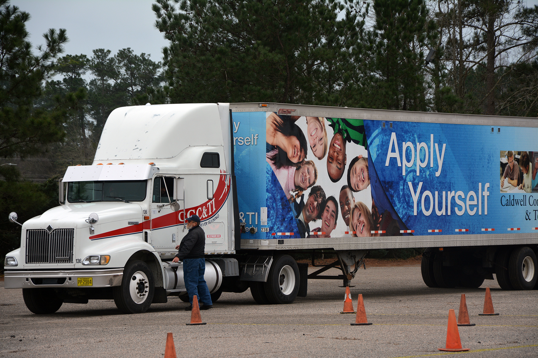 Truck driver instructor standing next to an 18-wheeler talking to student driver