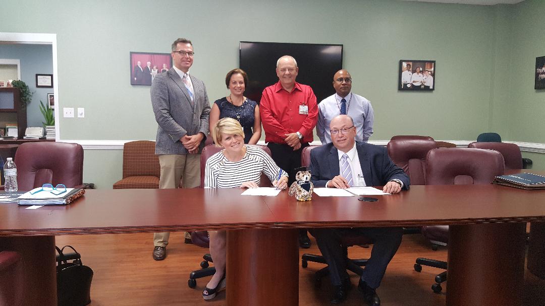 WGU NC Chancellor and RichmondCC President Dr. Dale McInnis sign an agreement while others look on.