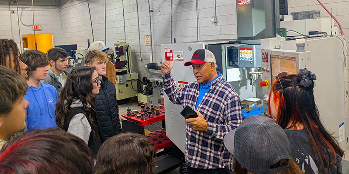 Machining instructor speaks to a group of high school students