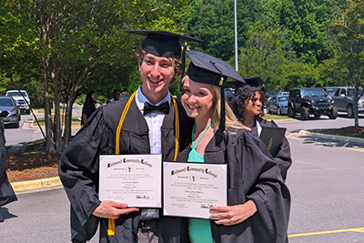Two dual enrollment students smiling happily during graduation