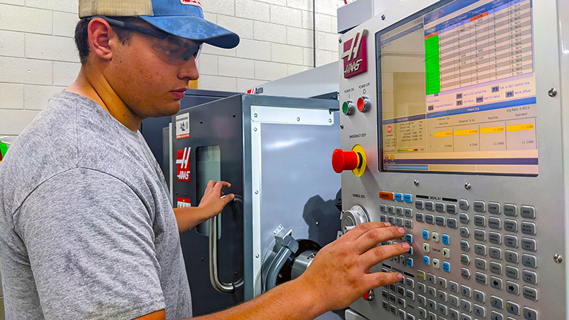 A machining student dials in a program on a CNC machine.