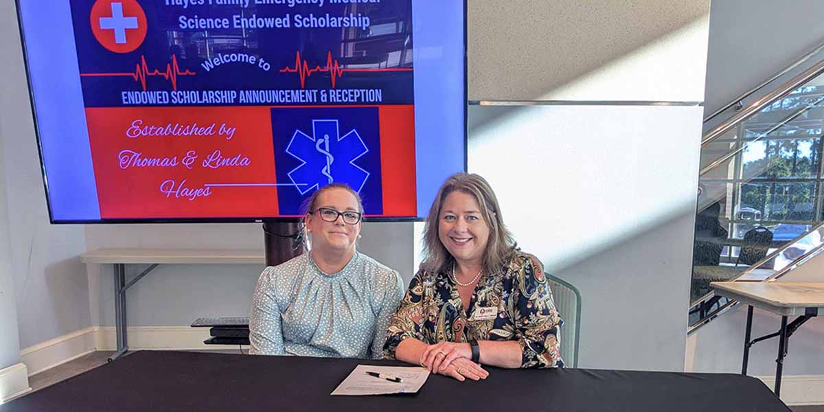 Jennifer Hayes sits with Dr. Wendy Kelly Jordan at a table with papers on the table.