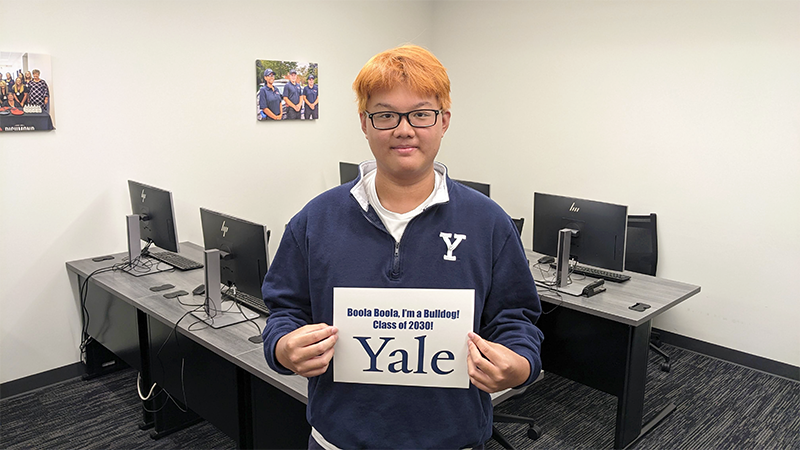 Andrew He holds up a sign saying Yale