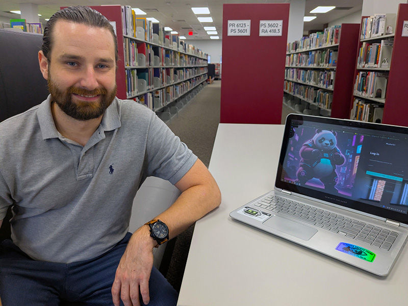 IT student Houston Almond sits at a table with his laptop.