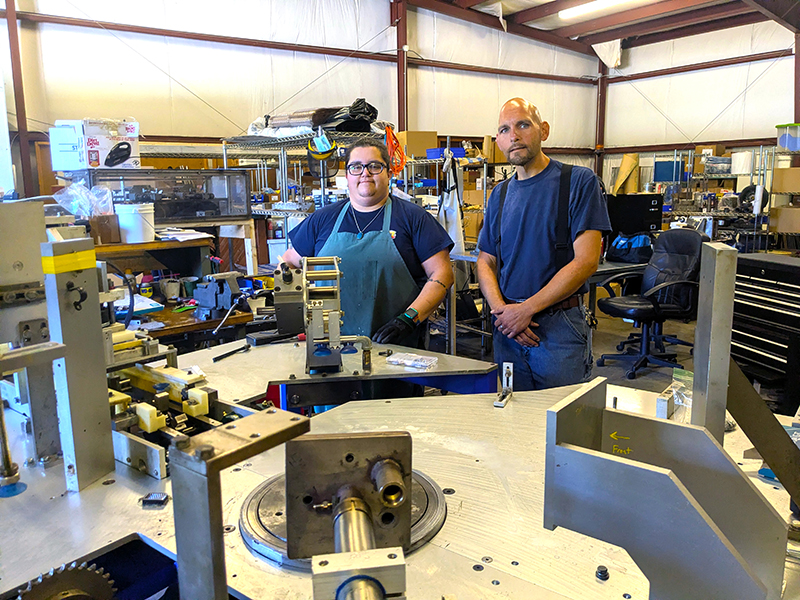 Industrial Systems technicians stand next to the machine they are assembling.