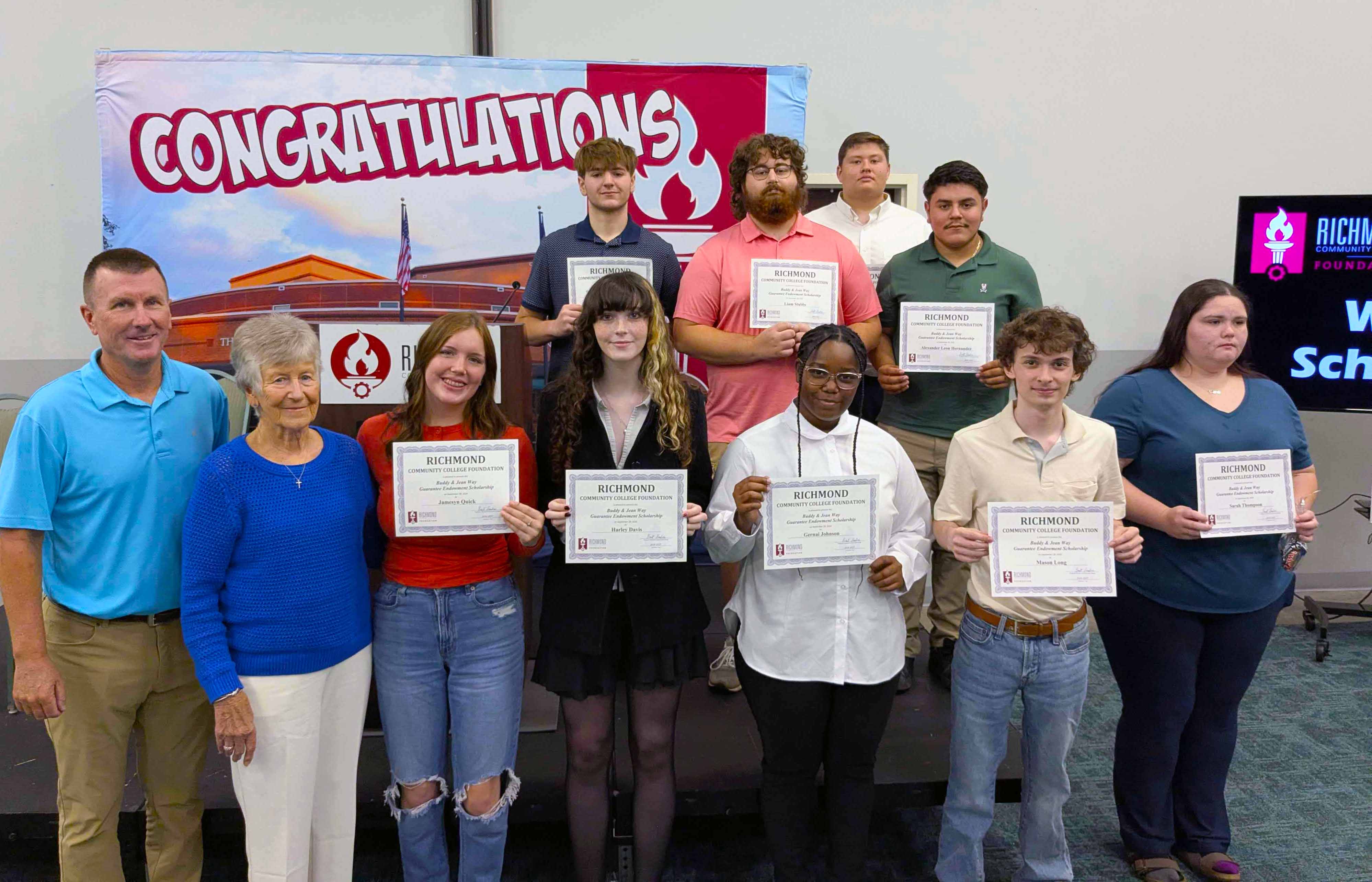 Students holding certificates stand with scholarship donors.
