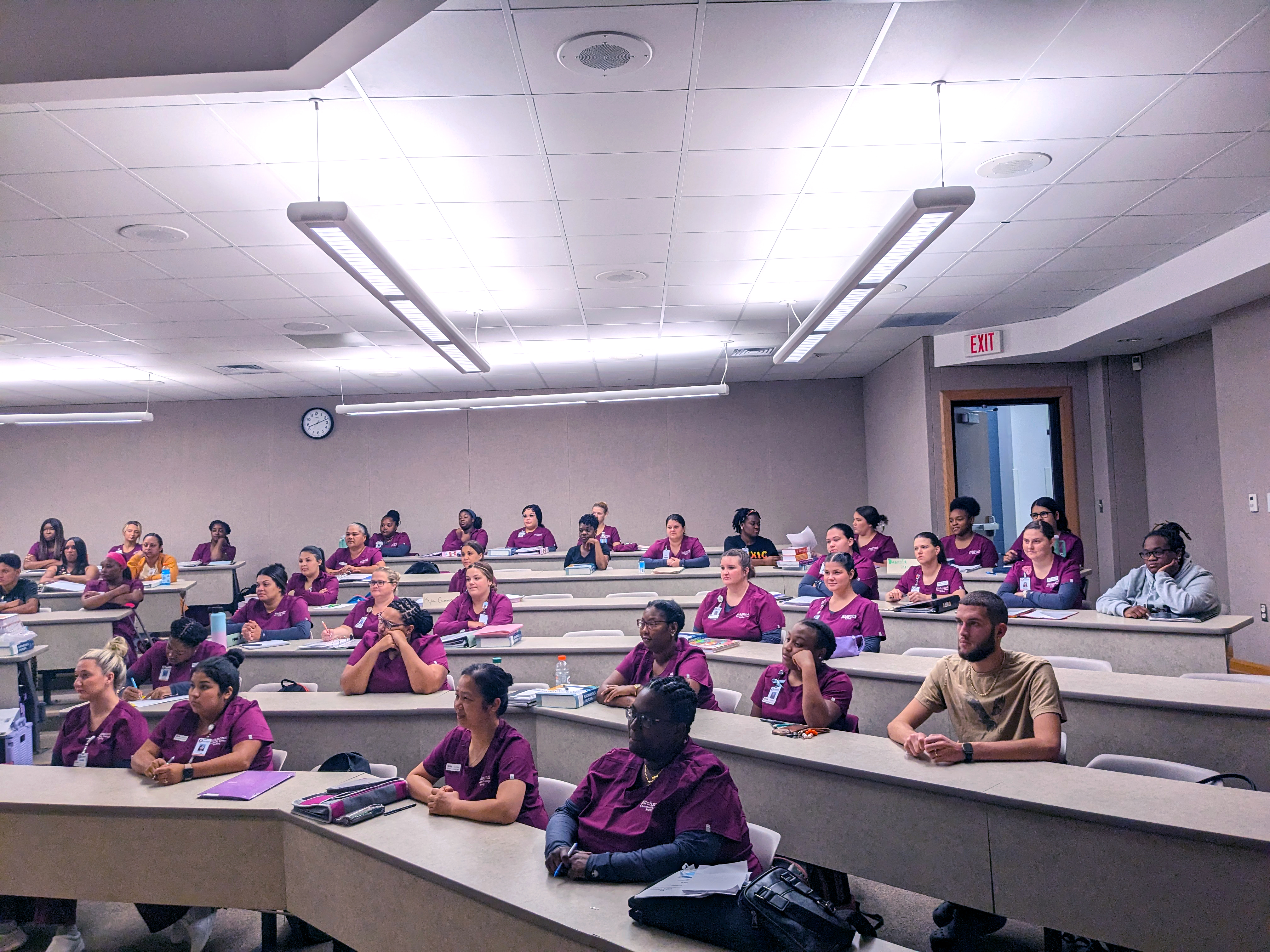 Many ADN students in uniform sit in a lecture hall in the Grimsley Building